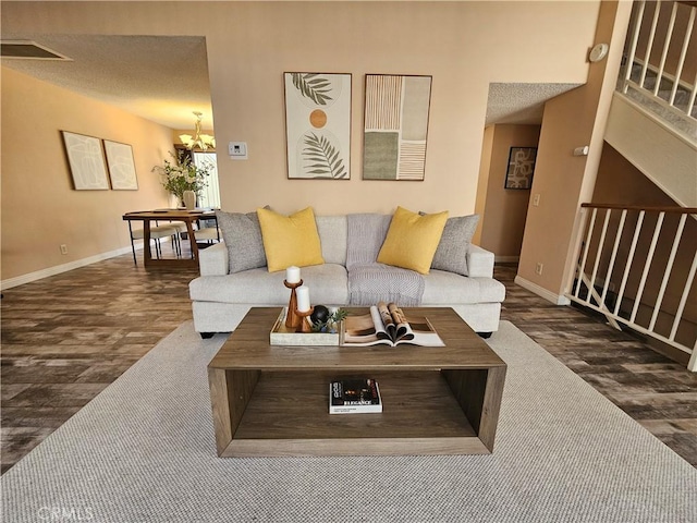 living room with a notable chandelier, wood finished floors, visible vents, and baseboards