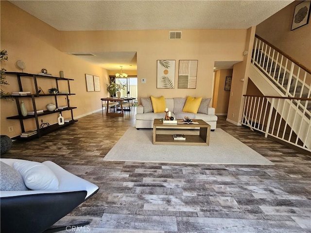 living room featuring visible vents, baseboards, an inviting chandelier, and wood finished floors