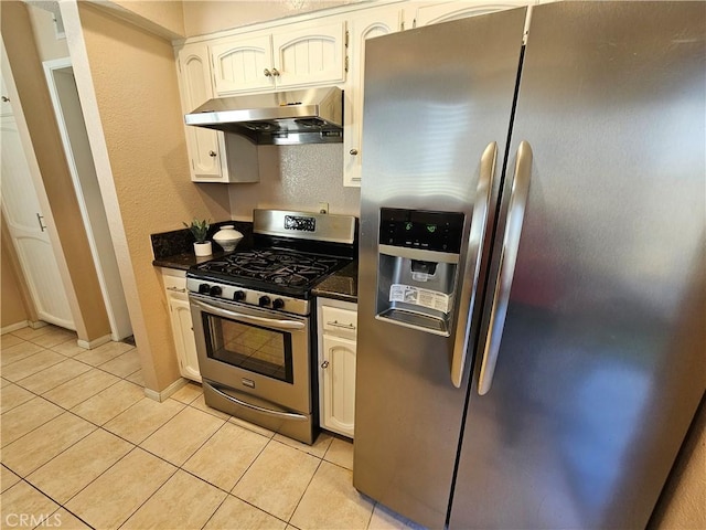 kitchen with white cabinetry, light tile patterned floors, dark stone counters, and appliances with stainless steel finishes