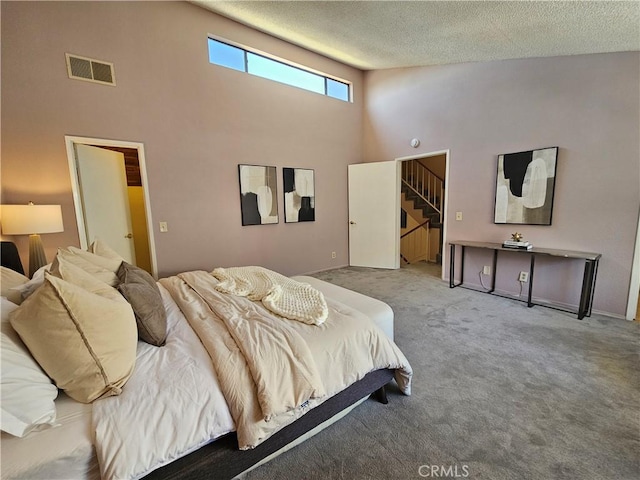 carpeted bedroom featuring a towering ceiling and a textured ceiling