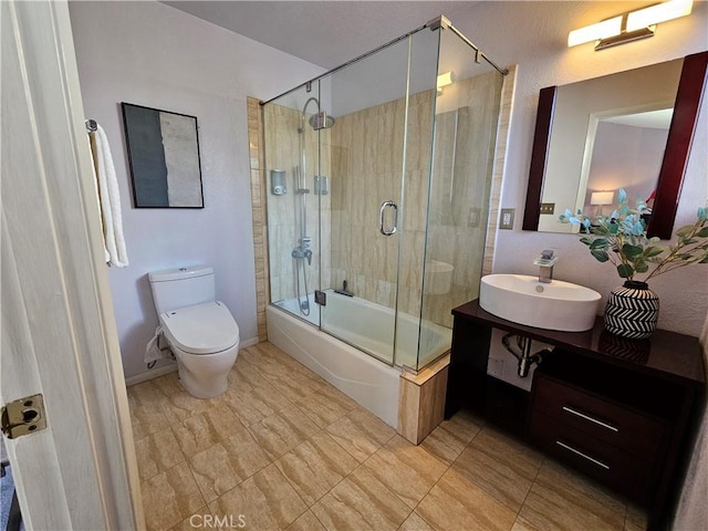 full bathroom featuring vanity, shower / bath combination with glass door, and toilet