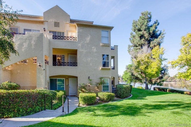 view of front facade with a balcony and a front lawn