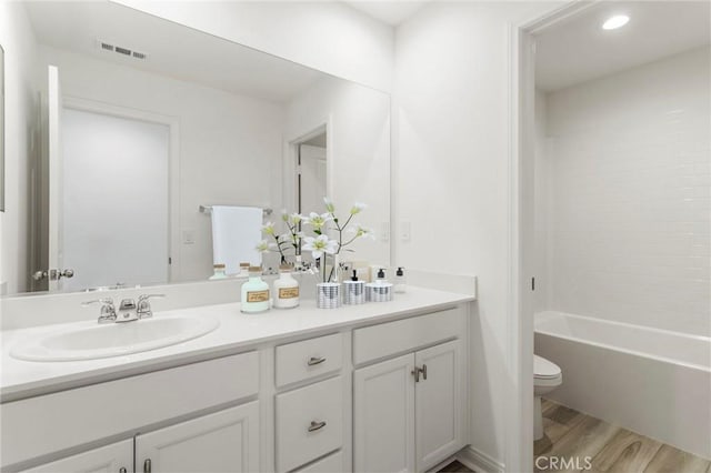 full bathroom with vanity, hardwood / wood-style floors, tub / shower combination, and toilet