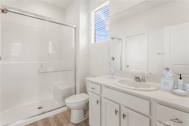 bathroom with wood-type flooring, toilet, an enclosed shower, and vanity