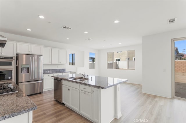 kitchen featuring white cabinetry, stainless steel appliances, sink, and an island with sink