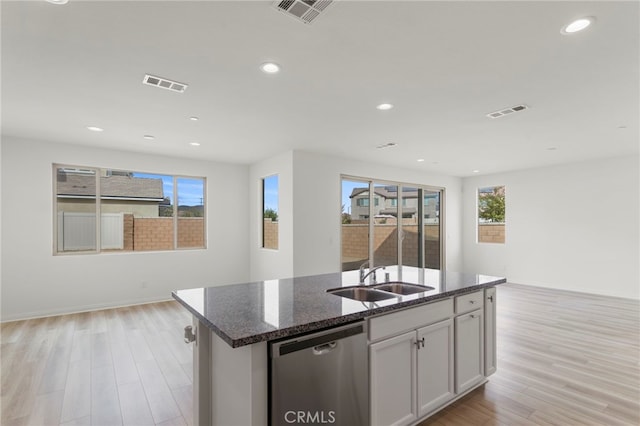 kitchen featuring dishwasher, an island with sink, sink, white cabinets, and light hardwood / wood-style flooring