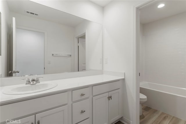 full bathroom featuring vanity, tiled shower / bath, hardwood / wood-style flooring, and toilet