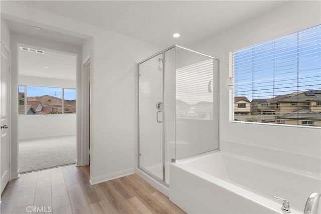 bathroom with hardwood / wood-style flooring and separate shower and tub