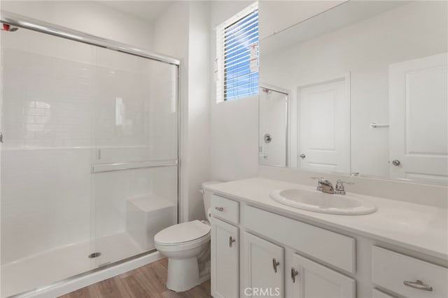 bathroom featuring vanity, hardwood / wood-style flooring, a shower with door, and toilet