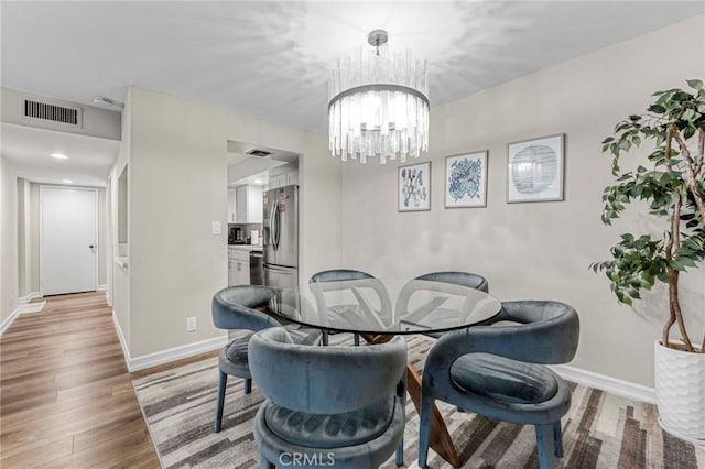 dining area with an inviting chandelier and wood-type flooring