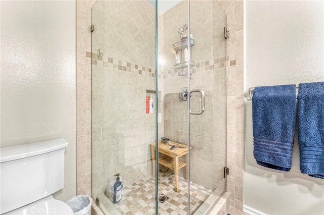 bathroom with a shower with shower door and toilet