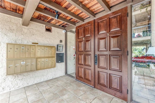 foyer with light tile patterned floors, beam ceiling, wooden ceiling, and a mail area