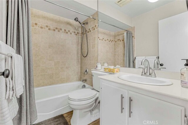 full bathroom featuring hardwood / wood-style flooring, vanity, shower / bath combination with curtain, and toilet