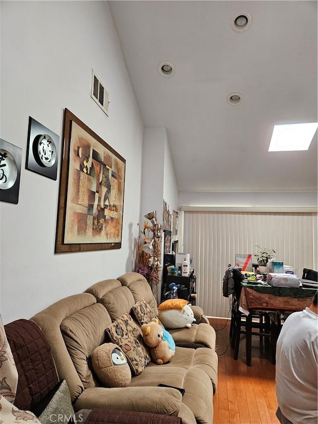 living room featuring wood-type flooring and vaulted ceiling with skylight