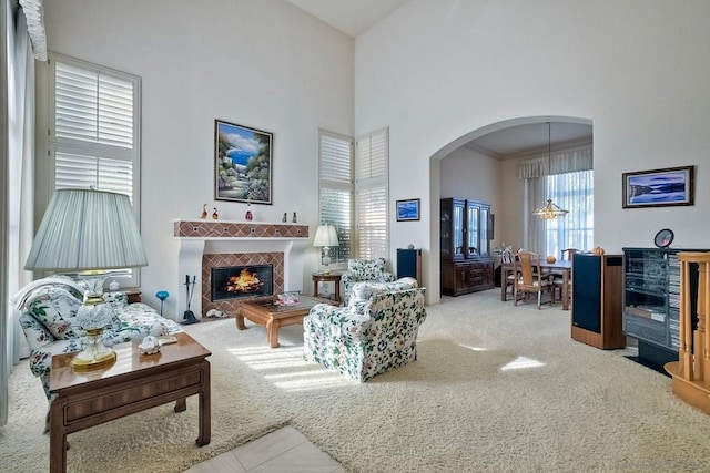 carpeted living room featuring a high ceiling, crown molding, a wealth of natural light, and a fireplace