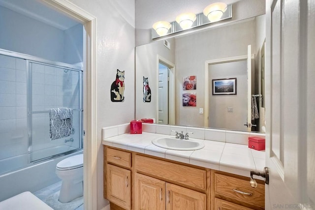 full bathroom with bath / shower combo with glass door, vanity, and toilet