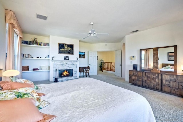 carpeted bedroom featuring ceiling fan and a high end fireplace