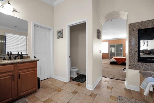 bathroom with toilet, vanity, and ornamental molding