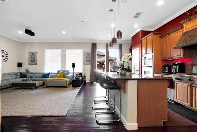 kitchen featuring white double oven, a center island, dark hardwood / wood-style flooring, a breakfast bar, and ornamental molding