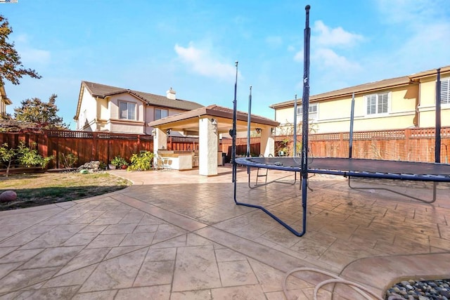 view of patio featuring a trampoline and an outdoor bar