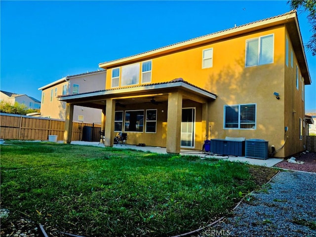 rear view of property with a patio, central AC, and a lawn