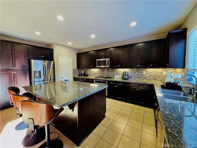 kitchen featuring light stone countertops, sink, a center island, and stainless steel appliances