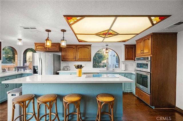 kitchen with appliances with stainless steel finishes, dark hardwood / wood-style flooring, a kitchen island, and sink