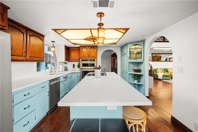 kitchen featuring pendant lighting, dark hardwood / wood-style flooring, a kitchen island with sink, and stainless steel appliances