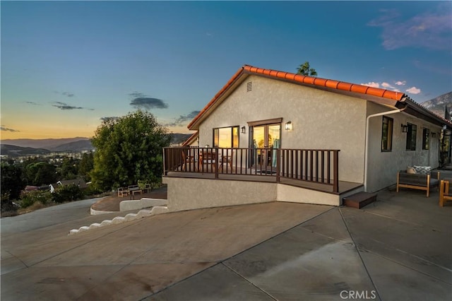 back house at dusk with a mountain view and a patio