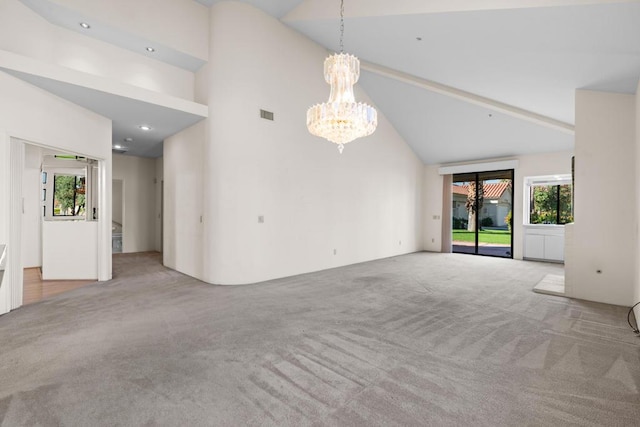 unfurnished living room featuring high vaulted ceiling, light colored carpet, and an inviting chandelier