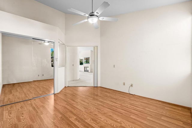 unfurnished bedroom with ceiling fan, a high ceiling, and light wood-type flooring