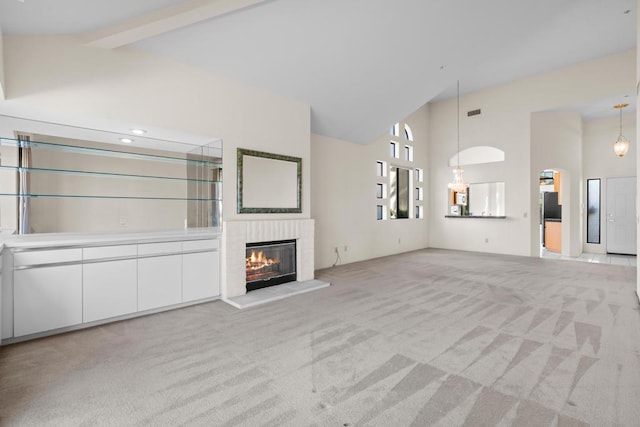 unfurnished living room featuring beamed ceiling, light colored carpet, and high vaulted ceiling