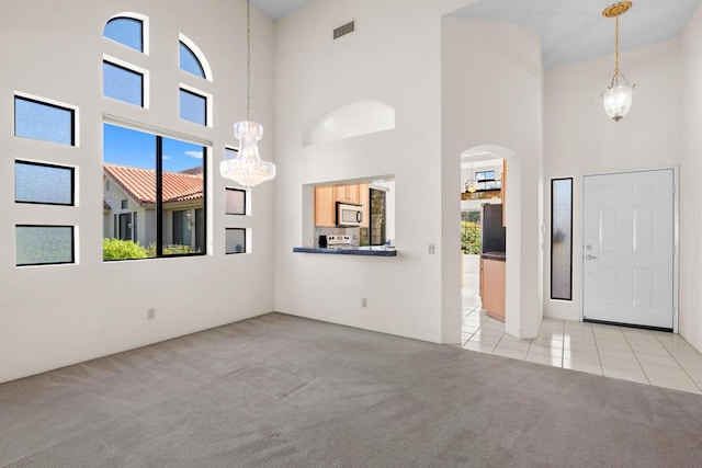 carpeted foyer entrance with a high ceiling and an inviting chandelier