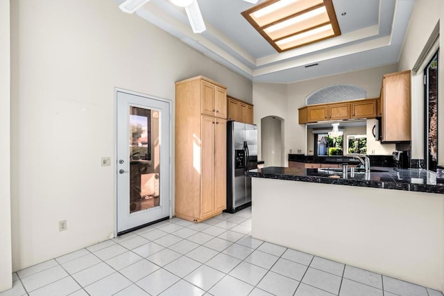 kitchen featuring sink, kitchen peninsula, stainless steel fridge, a tray ceiling, and light tile patterned floors