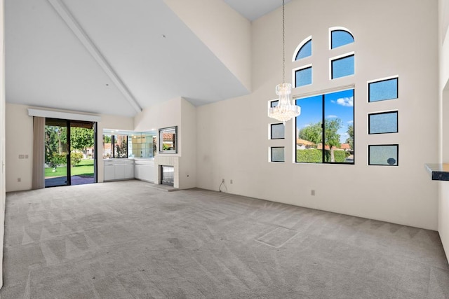 unfurnished living room featuring carpet flooring, high vaulted ceiling, a chandelier, and beam ceiling