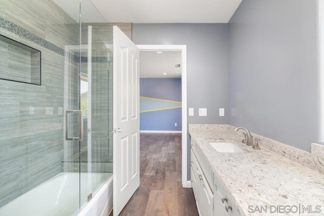 bathroom with hardwood / wood-style flooring, vanity, and enclosed tub / shower combo