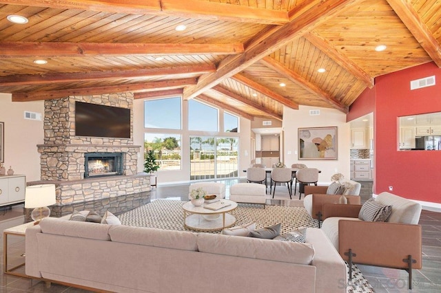 living room with beam ceiling, high vaulted ceiling, a stone fireplace, and wooden ceiling