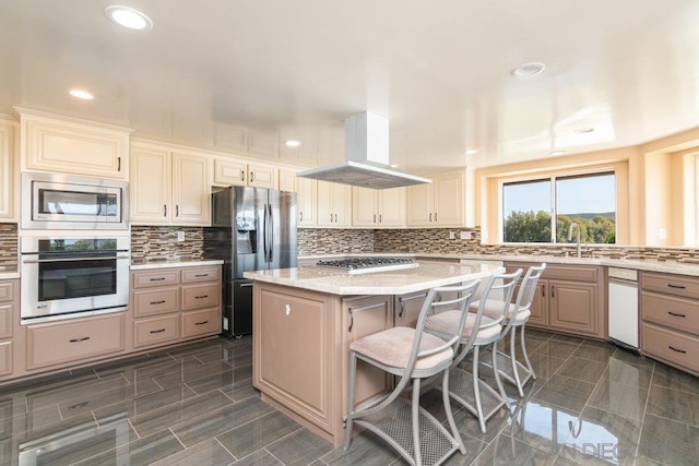 kitchen with stainless steel appliances, light stone counters, a kitchen bar, island range hood, and a kitchen island