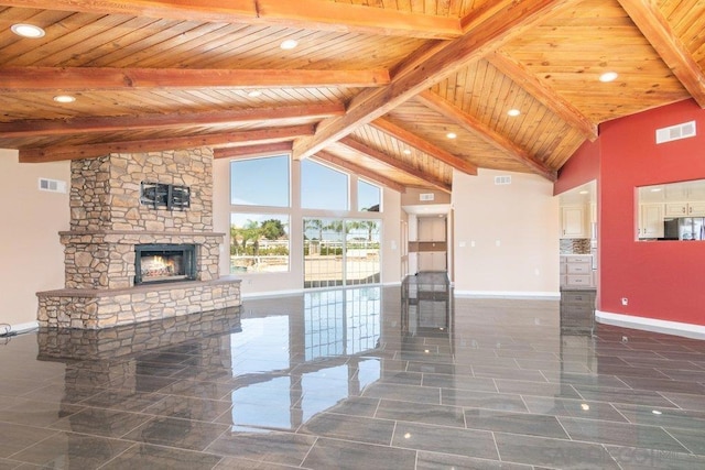 unfurnished living room with beam ceiling, a stone fireplace, high vaulted ceiling, and wooden ceiling