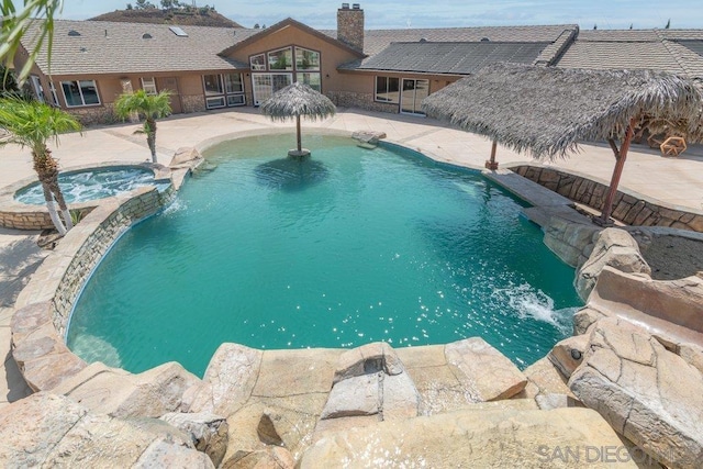 view of pool with pool water feature, a patio area, and an in ground hot tub