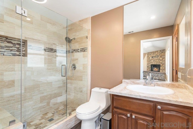 bathroom featuring vanity, toilet, an enclosed shower, and a stone fireplace