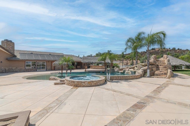 view of swimming pool with pool water feature and an in ground hot tub