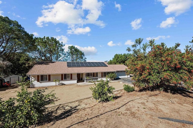 view of front of house featuring a storage unit, a porch, and solar panels