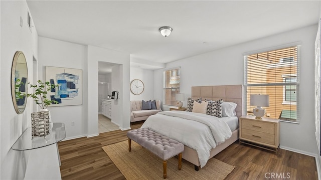 bedroom with multiple windows, ensuite bathroom, and dark wood-type flooring