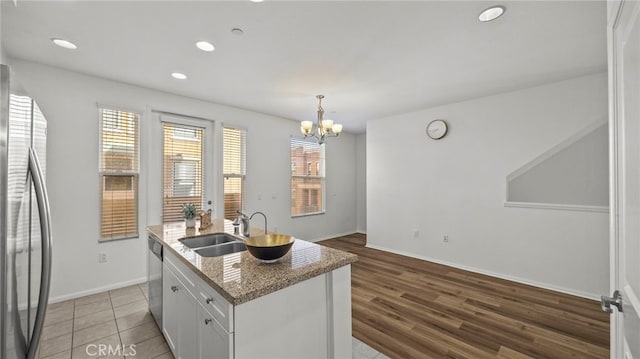 kitchen with stainless steel appliances, a kitchen island with sink, sink, wood-type flooring, and white cabinets