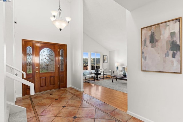 entryway with high vaulted ceiling, wood-type flooring, and a notable chandelier