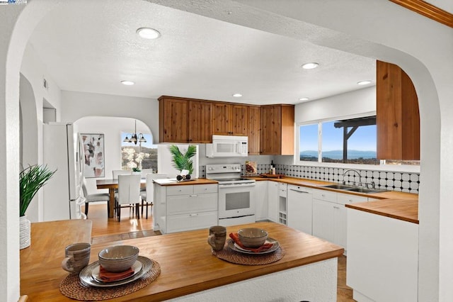 kitchen with tasteful backsplash, white cabinetry, sink, and white appliances