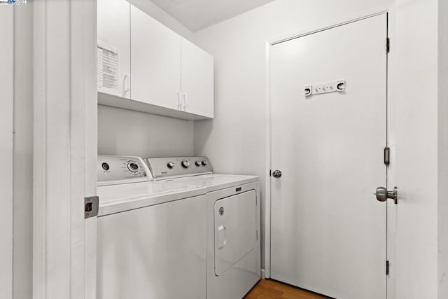 laundry area with washer and clothes dryer, cabinets, and light hardwood / wood-style floors