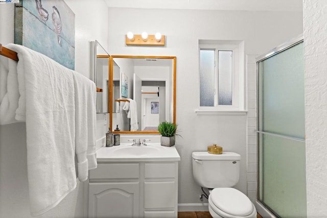 bathroom featuring vanity, toilet, and a shower with shower door