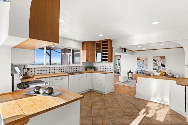 kitchen with white cabinets, stove, white dishwasher, and kitchen peninsula